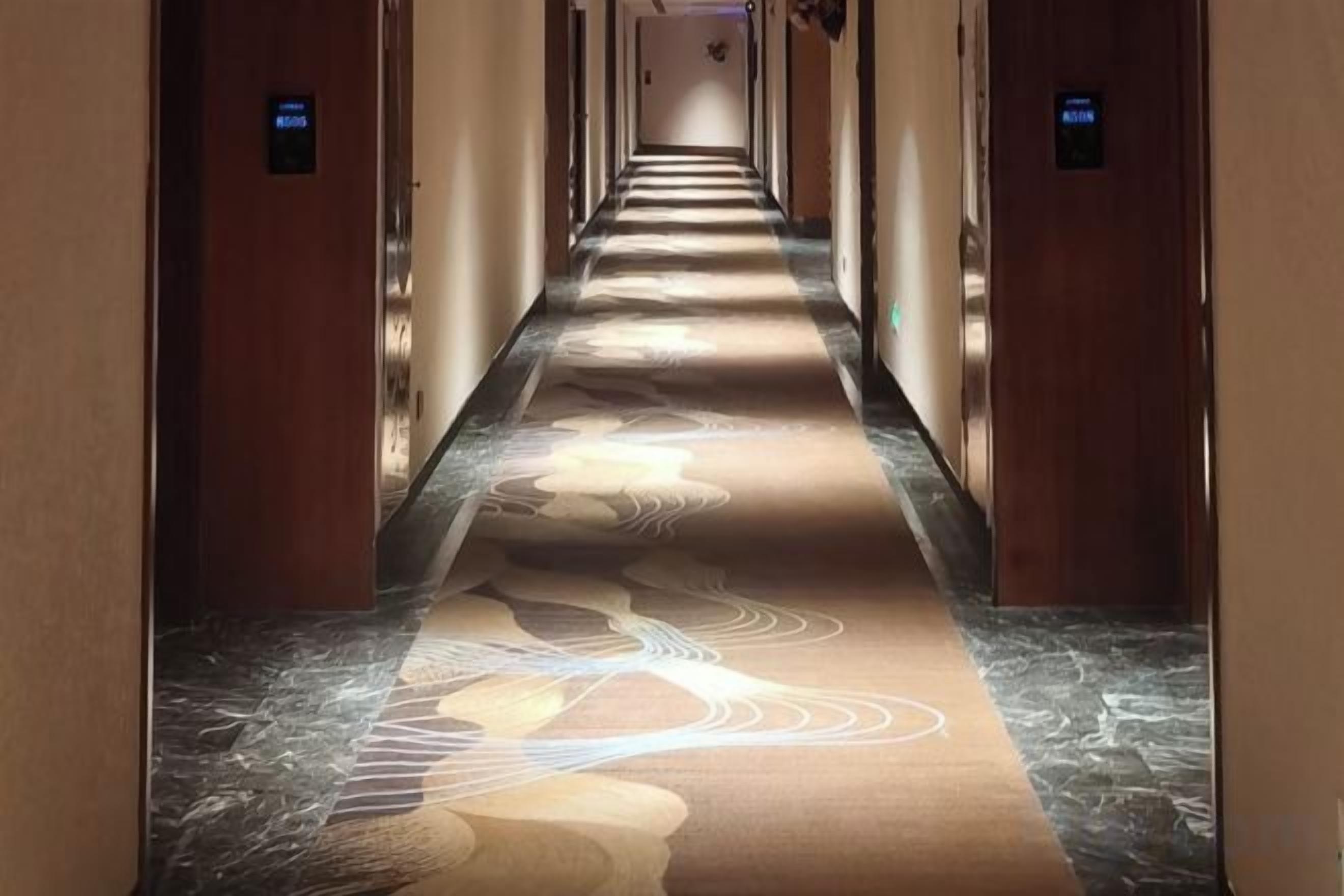 Um corredor de hotel com piso coberto por carpete e portas de ambos os lados.