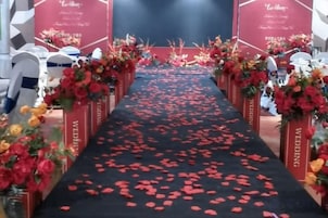 Un pasillo con piso alfombrado y decoraciones florales a ambos lados.