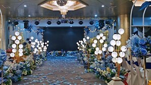 Un espacio interior con escenario, candelabros y decoración floral.