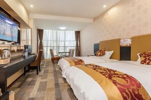 Quarto de hotel com uma cama, uma escrivaninha com computador, televisão e uma janela com cortinas.