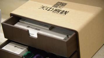 A brown box with Chinese characters and a barcode, containing several items including a white box and a green bottle.