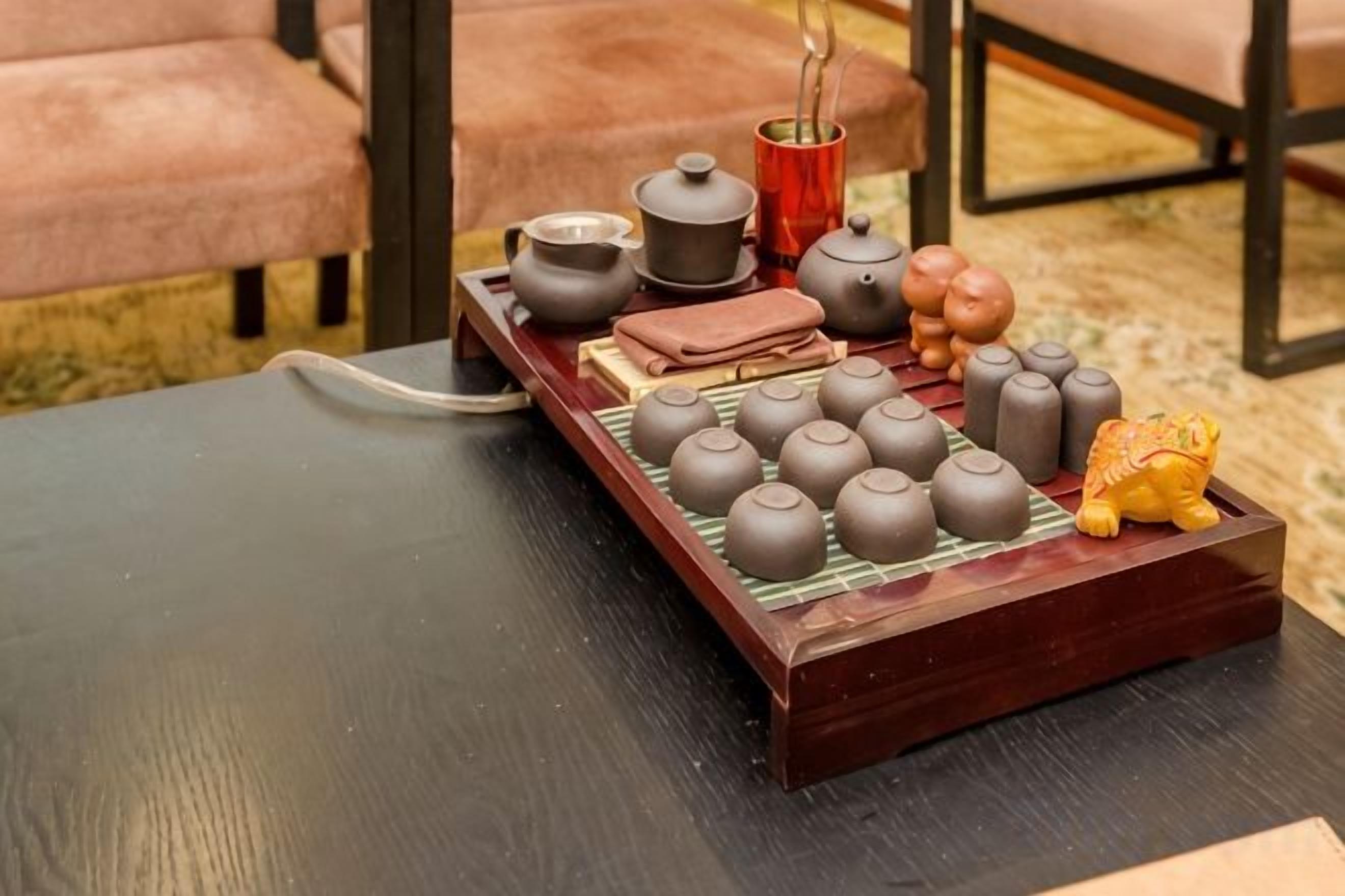 A traditional tea set with multiple teapots and cups arranged on a wooden tray.