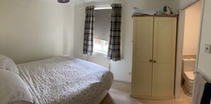 Cozy retreat with a single bed, wardrobe, and window with plaid curtains.
