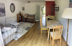 Relax in this inviting living room with a sofa, table, and chair, plus a dining area with a wooden table and chairs.