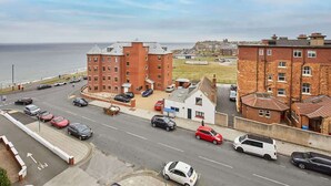 A coastal road with a mix of residential buildings and a large brick structure. - Host & Stay | Boutique Balcony (Whitby)