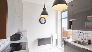 A modern kitchen with a built-in oven, a wall-mounted clock, pendant lighting, and a large window. - Host & Stay | Boutique Balcony (Whitby)