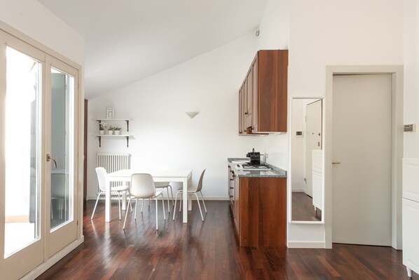 Une cuisine moderne avec des meubles en bois, un plan de travail blanc et un coin repas comprenant une table et des chaises blanches.