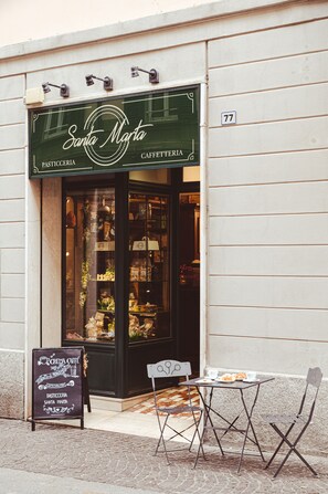 Une devanture de magasin avec une enseigne indiquant « Santa Marta Caffetteria » et le numéro « 77 » au-dessus de la porte.