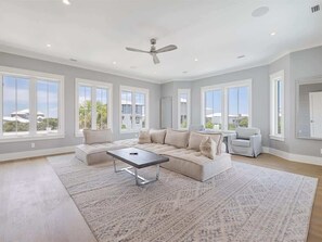 A spacious living room with a large sofa, a coffee table, and a ceiling fan.