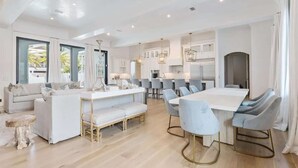 Une cuisine moderne avec des meubles blancs, un îlot central et des tabourets de bar.