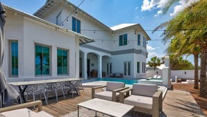 Une maison moderne dotée d’une piscine, d’un espace salon extérieur et d’un patio couvert.