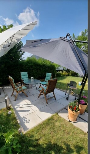 An outdoor patio with a table and chairs, surrounded by a large umbrella.
