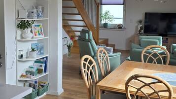 Ein stilvolles Wohnzimmer mit Essbereich, Holzboden und einer Treppe.