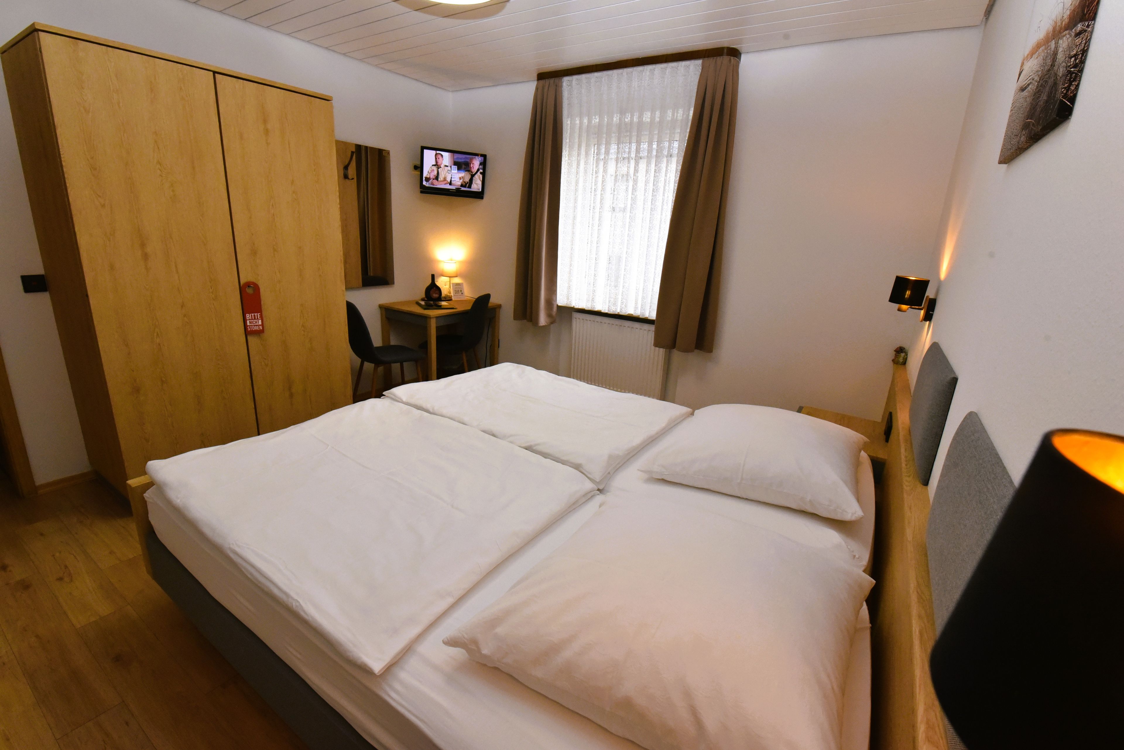 Una habitación de hotel con cama, escritorio, televisor y armario.