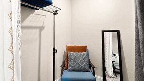 Huoneen nurkassa on tuoli, peili ja pyykiteline.