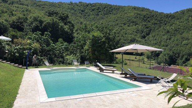 A swimming pool with lounge chairs and umbrellas, surrounded by lush greenery and hills. - VILLAROSA SPICCIANO Exclusive Villa with pool (Fivizzano/Spicciano)