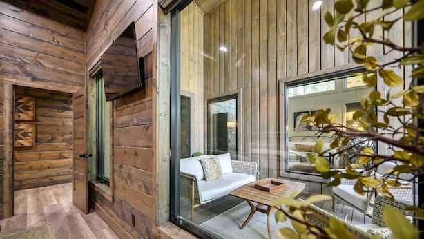 Ein gemütliches Zimmer mit Holzwänden, einem großen Fenster, einer Couch und einem Couchtisch.