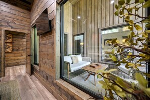 Ein gemütliches Zimmer mit Holzwänden, einem großen Fenster, einer Couch und einem Couchtisch.