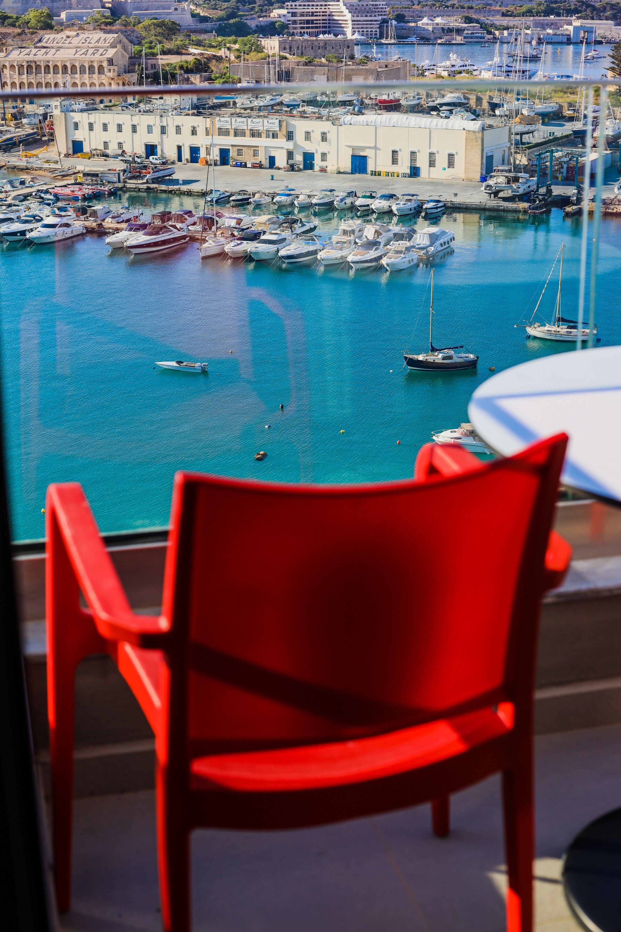 Una silla roja en una habitación con vistas a un puerto deportivo.