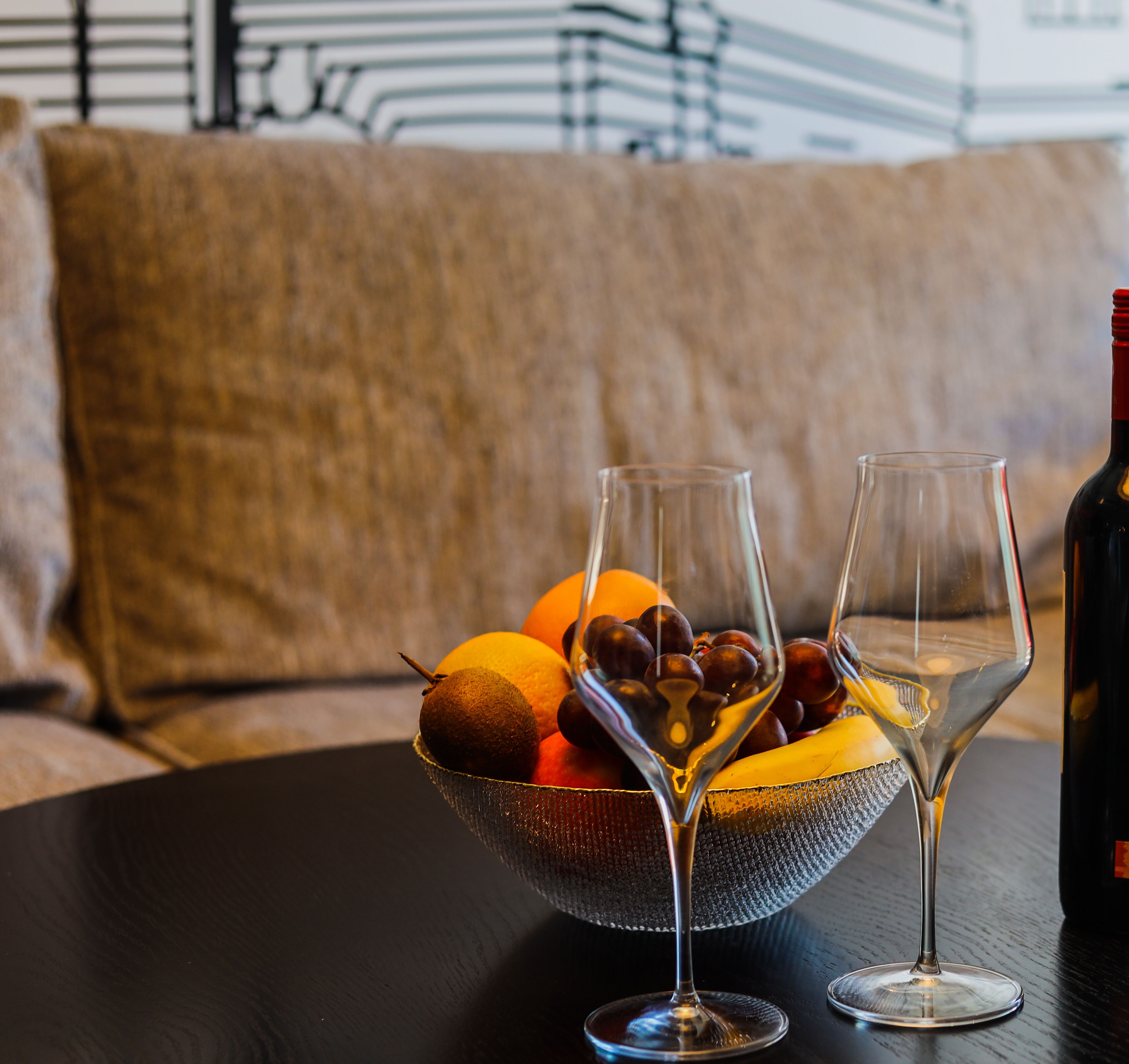 Un tazón de fruta y dos copas de vino sobre una mesa.