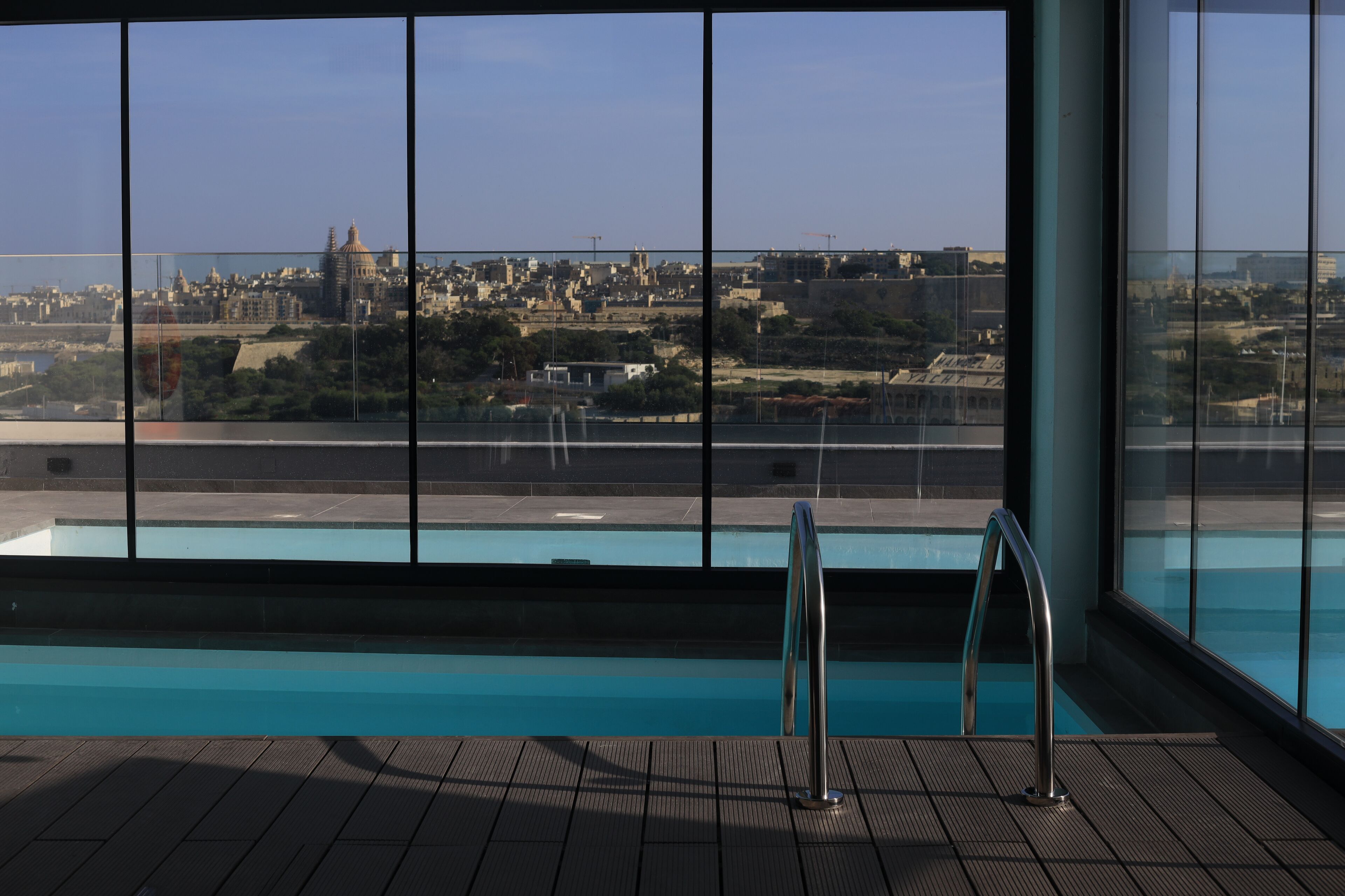 Una piscina interior con vistas a un paisaje urbano a través de amplios ventanales.