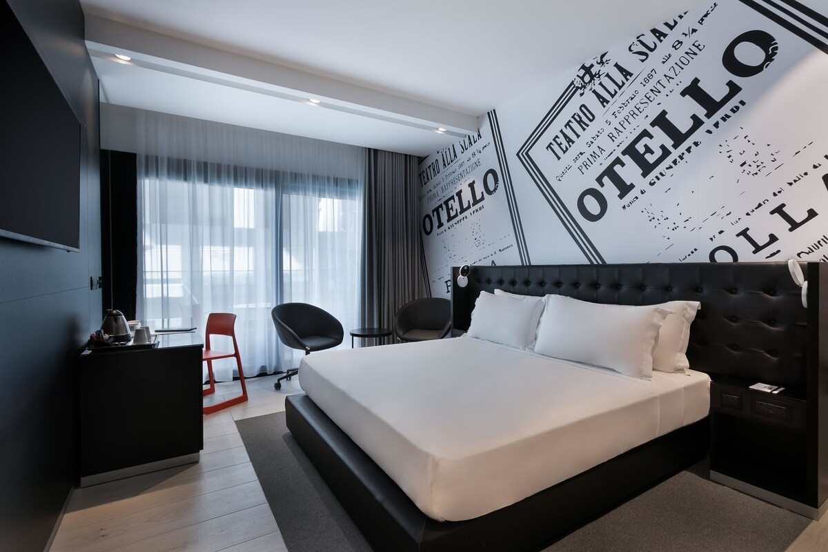 Una habitación de hotel moderna con una cama grande, un escritorio, una silla y un televisor.