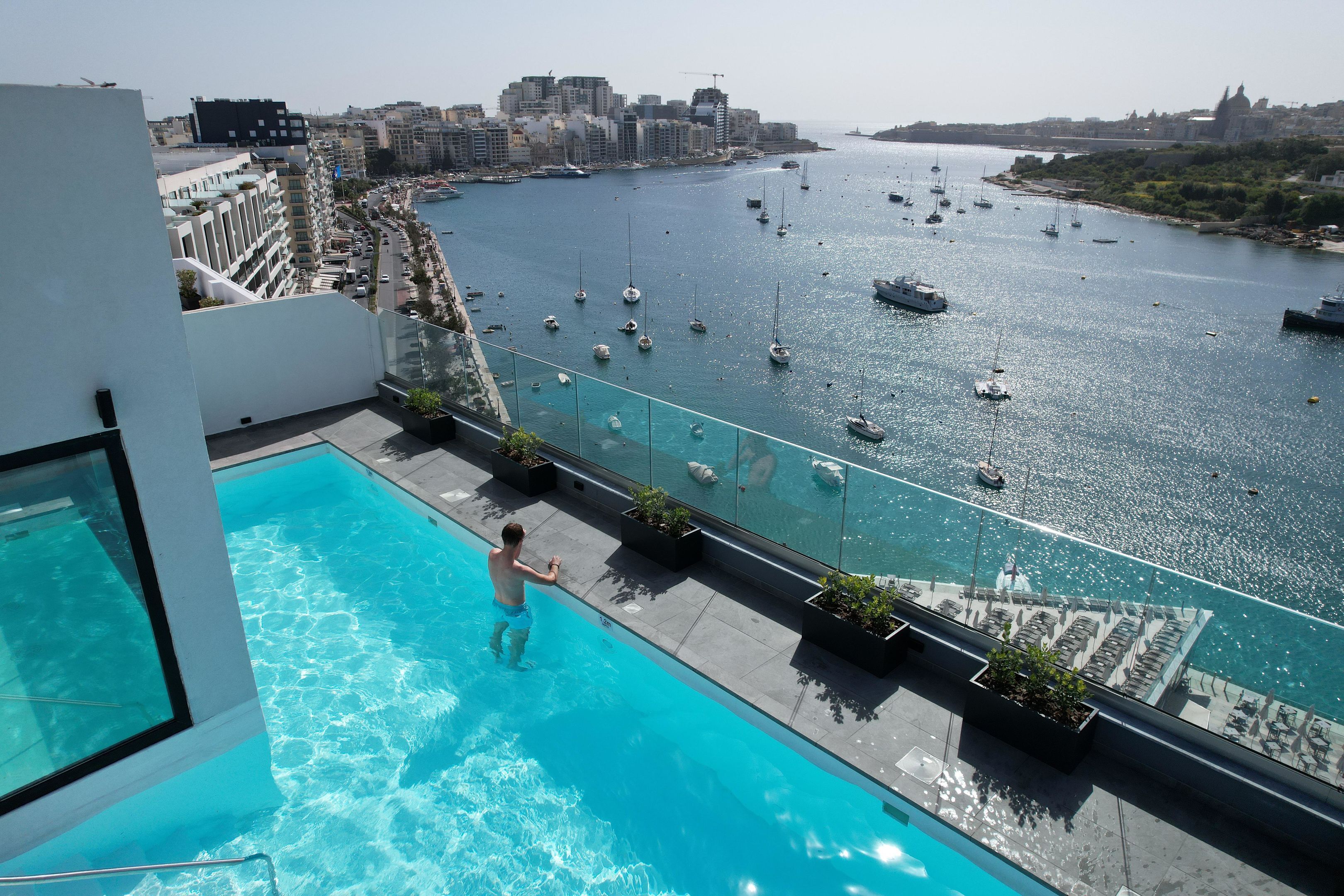 A rooftop pool with a view of a marina and cityscape.