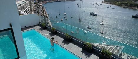 A rooftop pool with a view of a marina and cityscape.