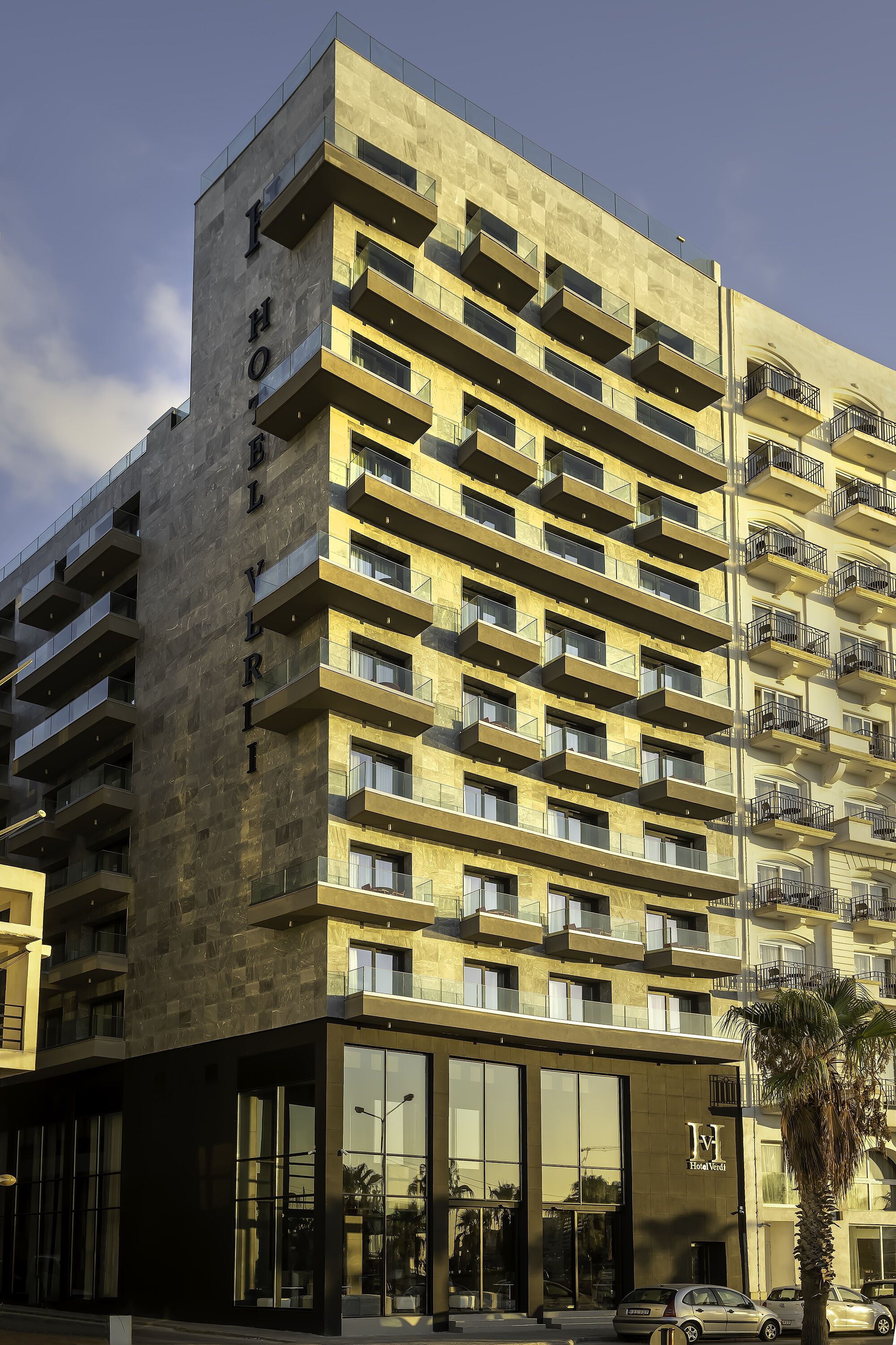 A modern hotel building with multiple balconies and a glass facade.