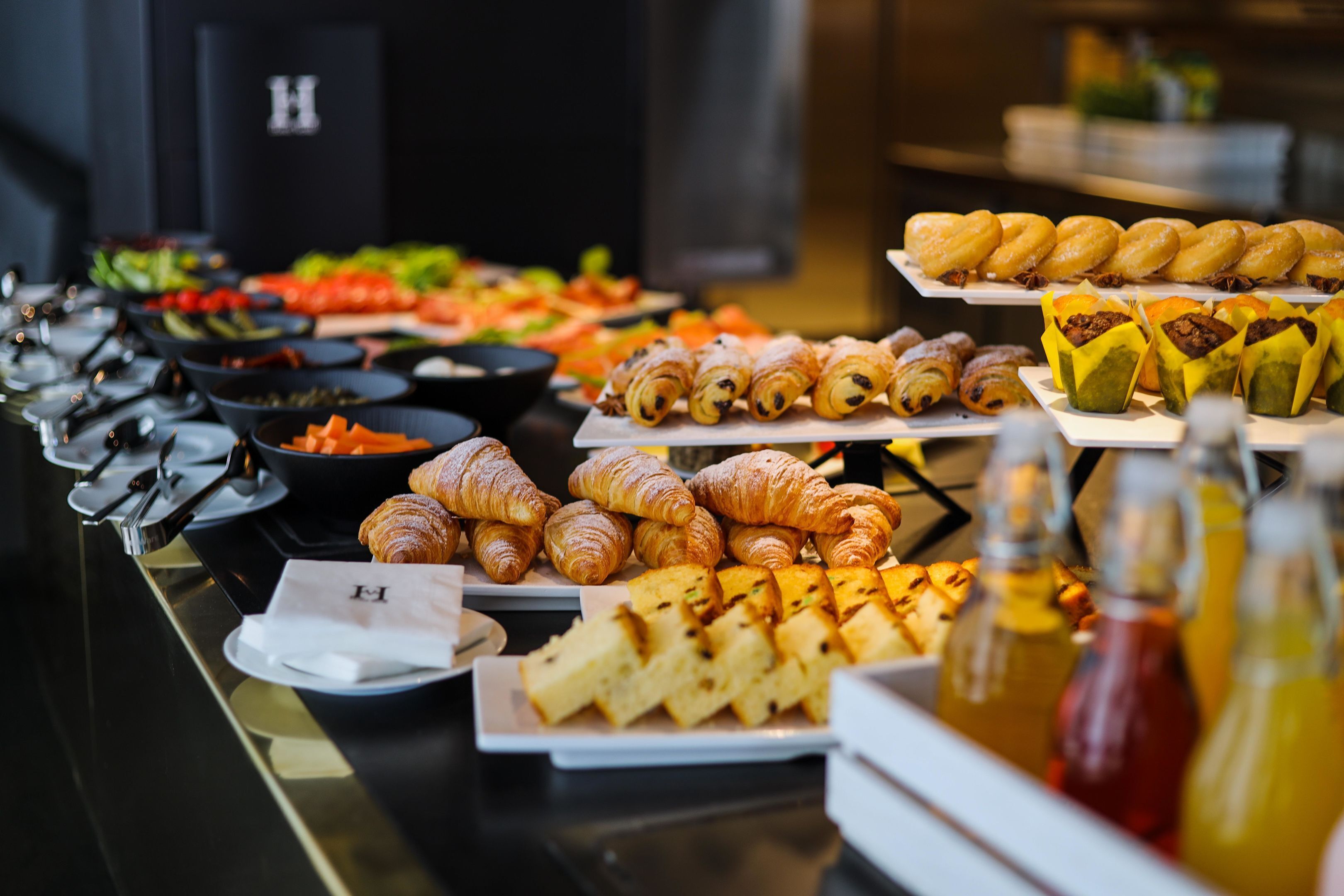 Un buffet proposant une variété de plats, notamment des pâtisseries, des salades et des boissons.