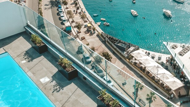 Una piscina en la azotea con vistas a un puerto deportivo lleno de barcos.