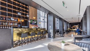 Un área de bar moderna con barra, asientos y un ventanal amplio.