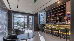 Un área de bar moderna con mostrador, asientos y un ventanal que ofrece vistas de la ciudad.