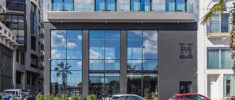 A hotel with a modern glass facade, multiple balconies, and a clear sky.