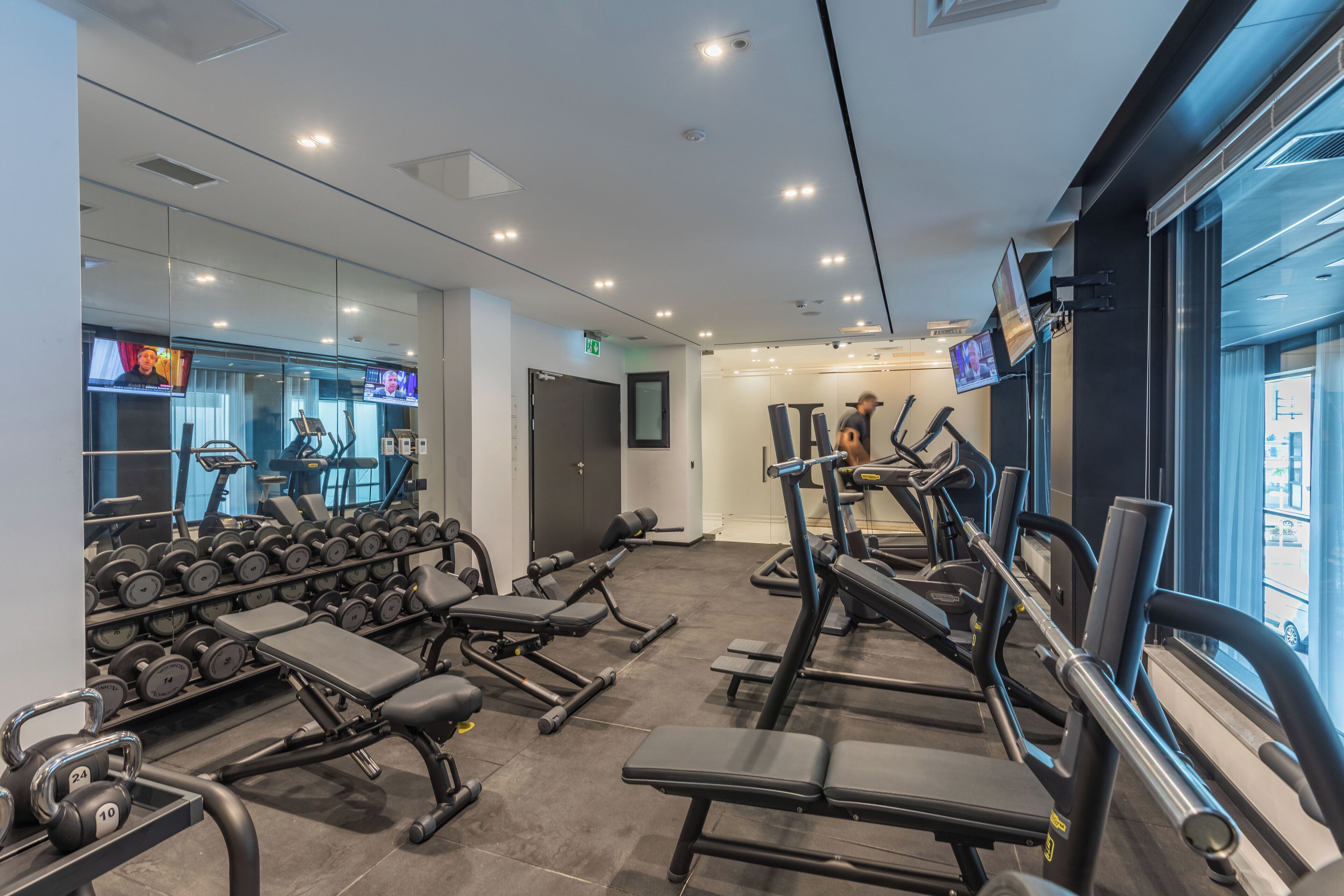 A modern gym with various exercise equipment, including dumbbells, benches, and treadmills.