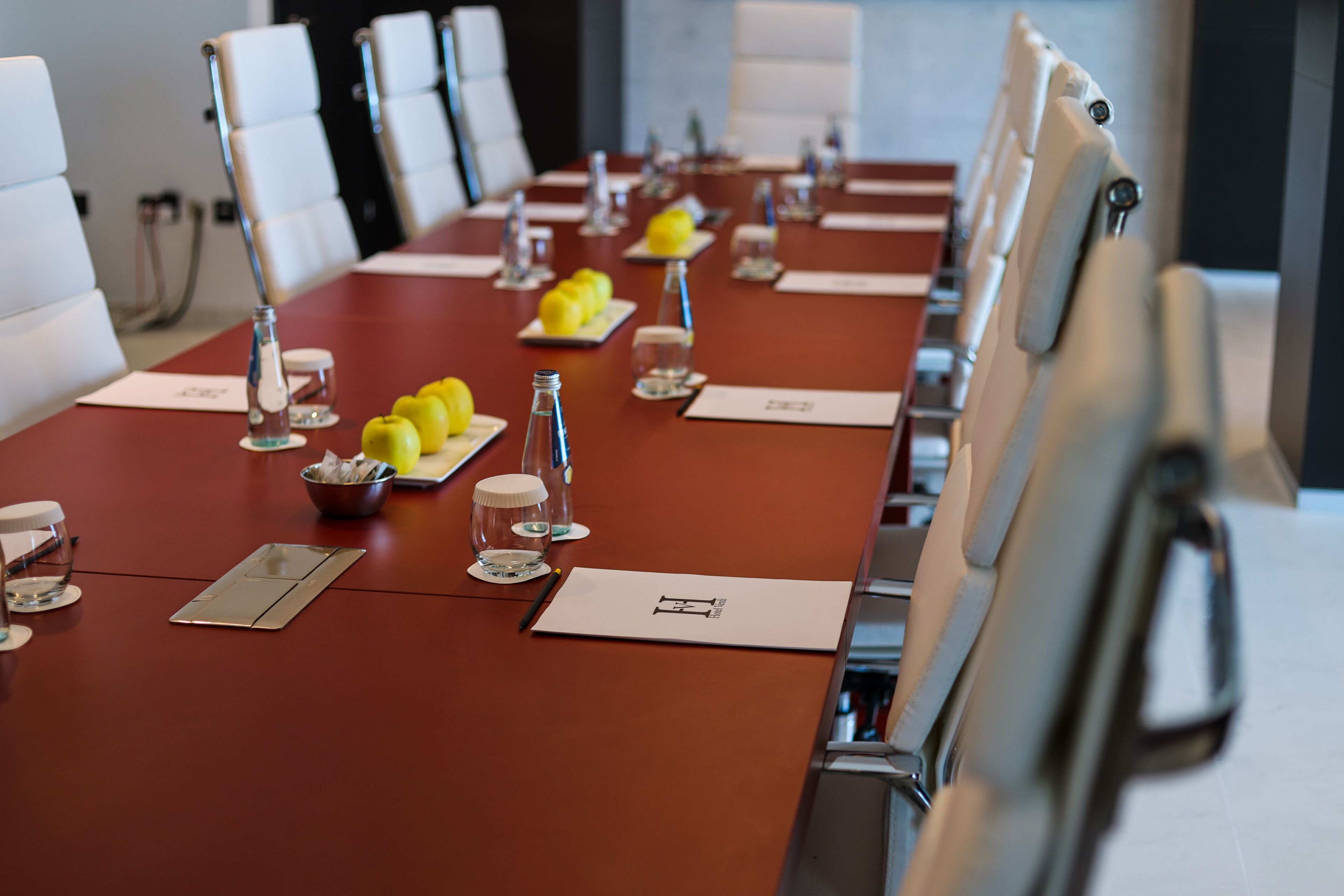 Una sala de conferencias con una larga mesa, sillas blancas y tarjetas con nombres.