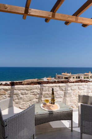 A stone wall with a table and chairs, overlooking the sea. - Suite Leon, Seafront Residence (Panormo)