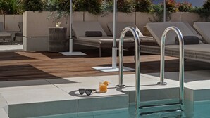 A poolside area with lounge chairs, a pool, and a small table with sunglasses and a drink. - UMusic Hotel Madrid (Madrid)