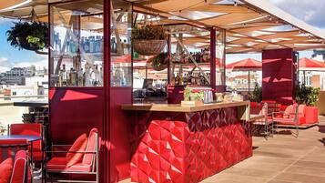 An outdoor bar area with red seating and a counter displaying various bottles.