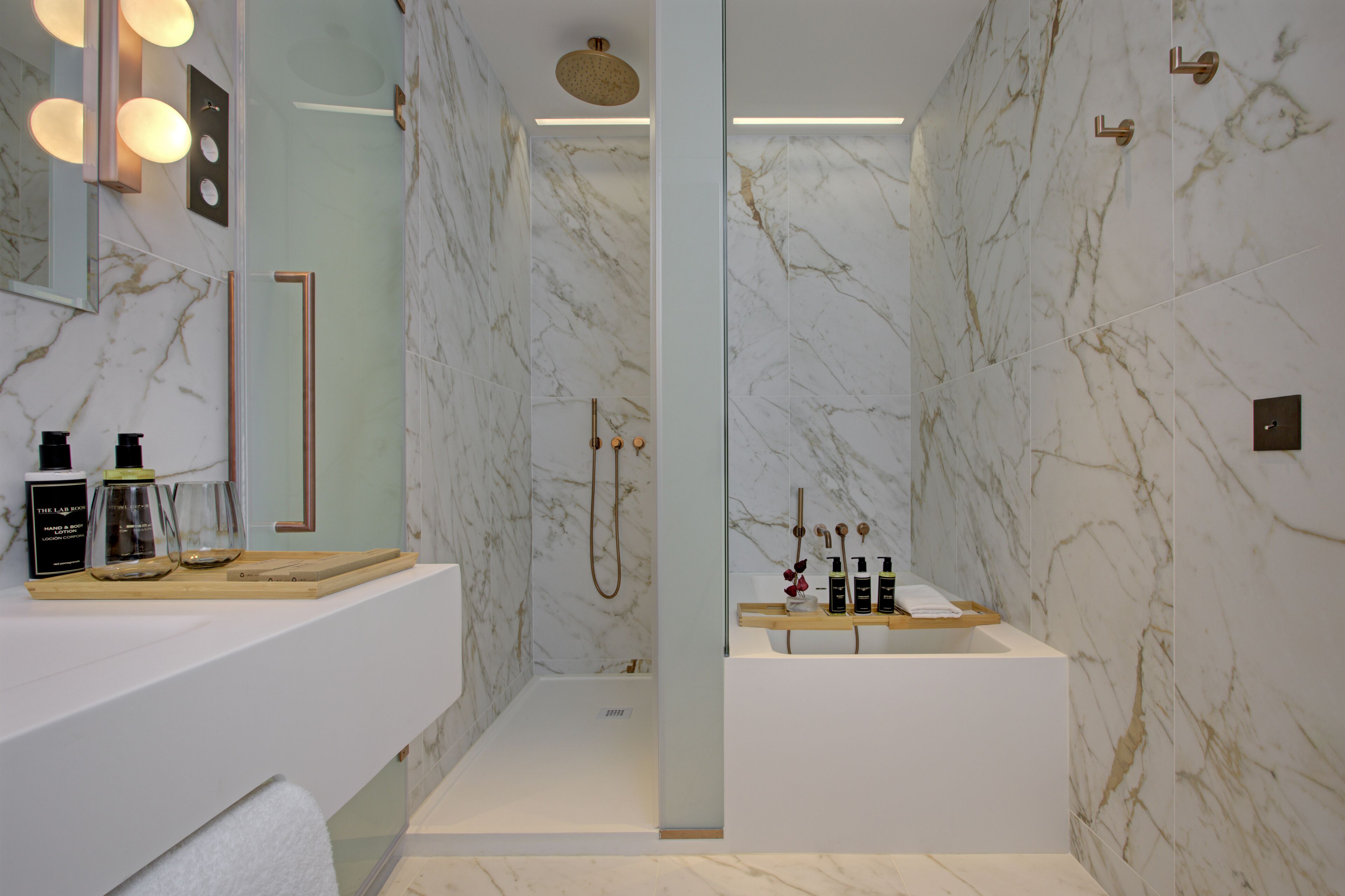 Un bagno moderno con pareti in marmo, cabina doccia in vetro e mobile lavabo con articoli da toilette.