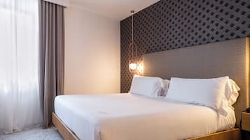 Habitación de hotel moderna con una cama grande, cabecero de madera y una pared decorativa con estampado.
