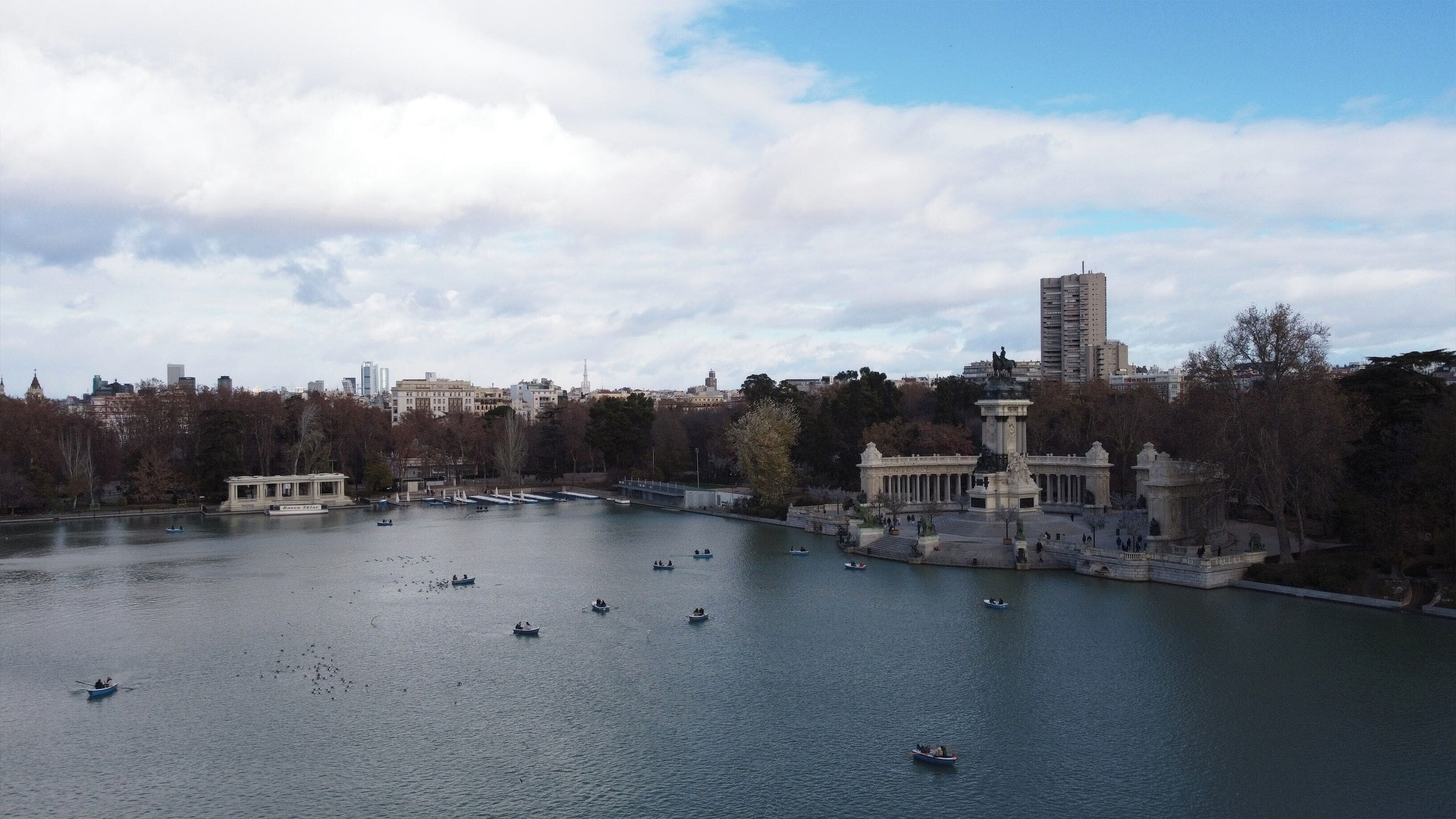 A large body of water with boats, a historic building with statues, and a cityscape in the background.