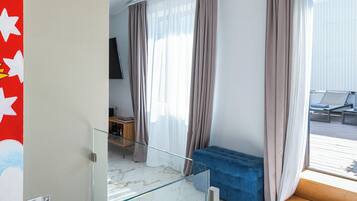 Una habitación de hotel moderna con un separador de vidrio, un sofá azul y vistas al área exterior.