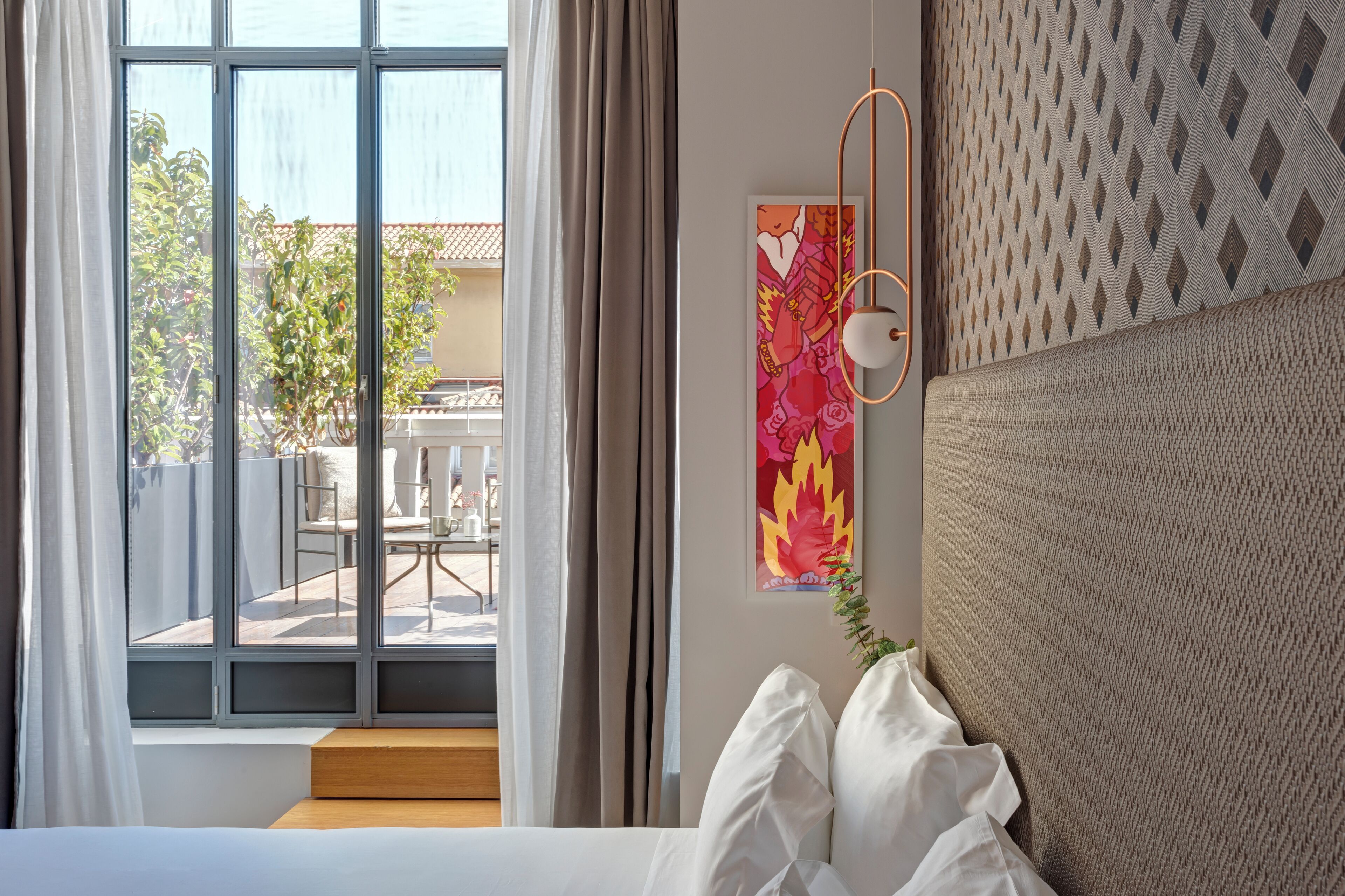 A bedroom with a large window, a view of the outdoor patio, and a wall-mounted artwork.