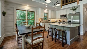 Una cocina con armarios de madera, una isla central y una zona de comedor con mesa y sillas.