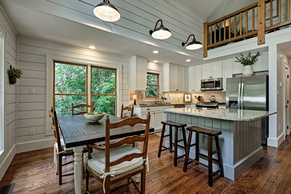A kitchen with wooden cabinets, a central island, and a dining area with a table and chairs.