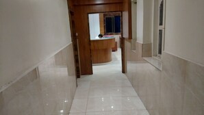 Un pasillo con mostrador de recepción de madera, un espejo y suelo de baldosas.