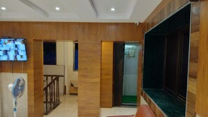Una sala de estar moderna con una pared de acento de madera, un sofá de cuero, un televisor de pantalla plana y un ventilador de pie.