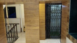 Un pasillo con piso de madera, una reja metálica y una escalera con barandillas de madera.