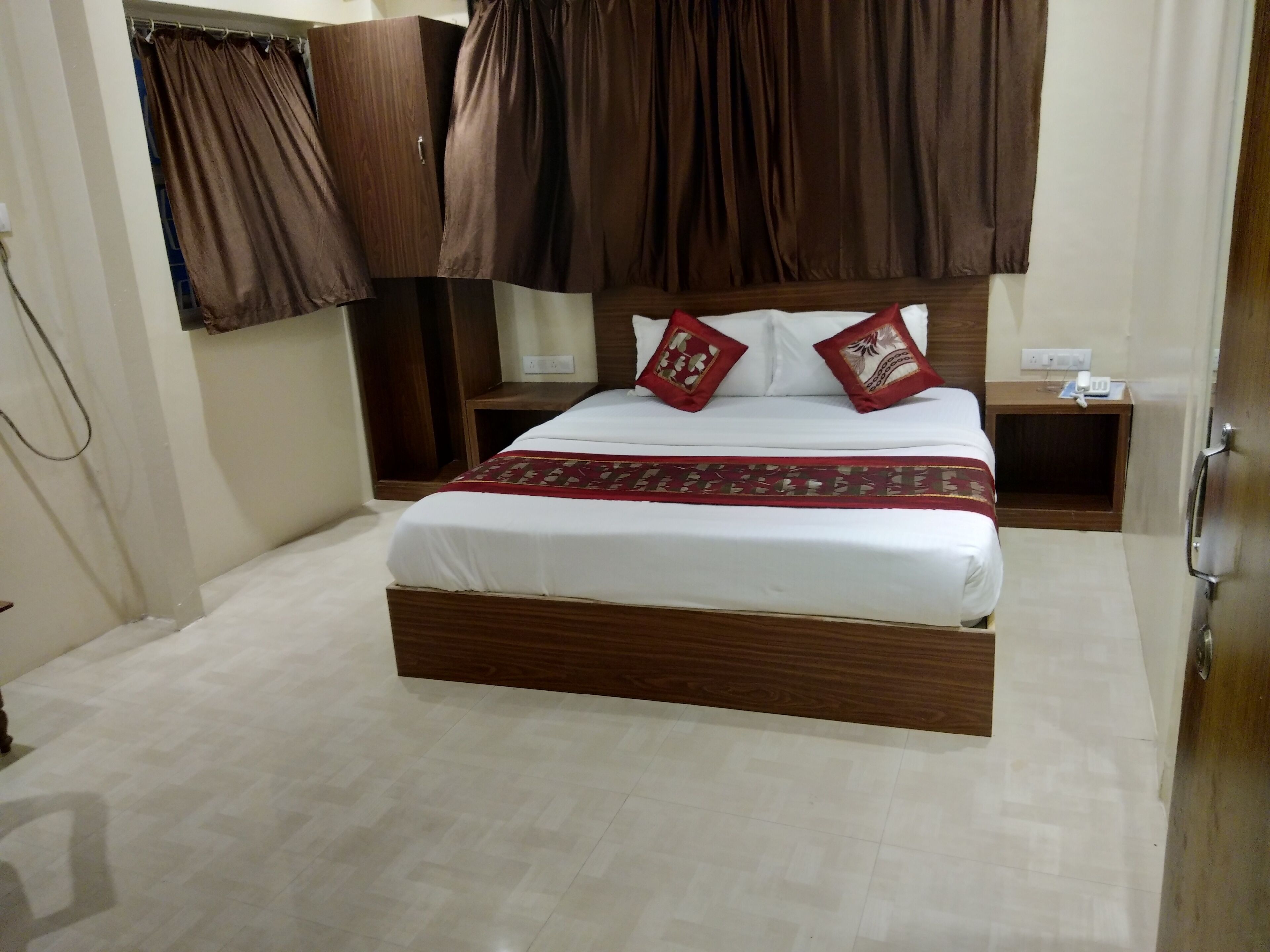 Ein Schlafzimmer mit einem hölzernen Bett, weißer Bettwäsche und braunen Vorhängen.